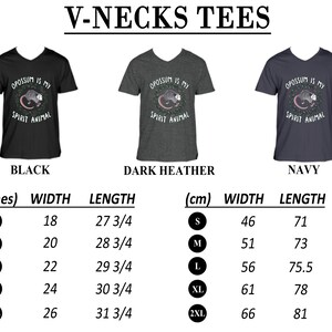May include: A V-neck t-shirt with a graphic of an opossum and the text "Opossum is my spirit animal". The shirt is available in black, dark heather, and navy. The size chart shows the width and length of the shirt in inches and centimeters.