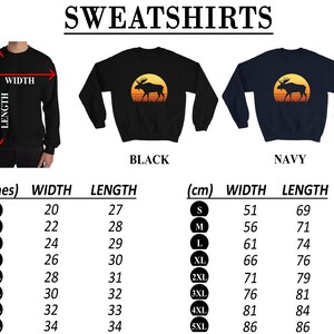 May include: Black and navy sweatshirts with a moose silhouette design against a sunset. The image includes size charts in inches and centimeters, detailing width and length measurements for sizes S to 5XL. The word SWEATSHIRTS is at the top.