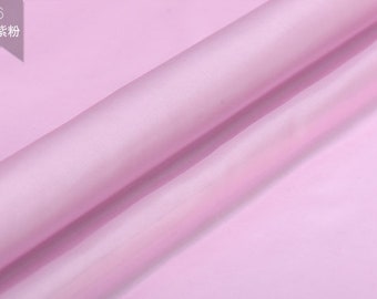 May include: A close-up of a light pink fabric. The fabric is smooth and silky.
