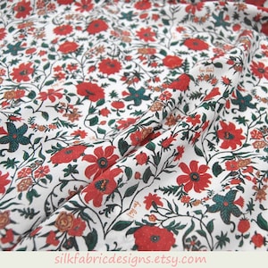 May include: White cotton fabric with a red and green floral print. The fabric features a repeating pattern of small flowers and leaves.