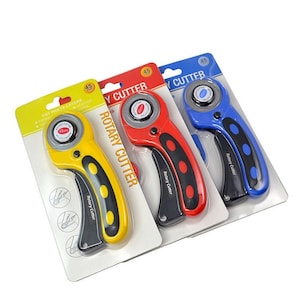 May include: Three rotary cutters with yellow, red, and blue handles. Each cutter has a 45mm blade and a safety lock. The packaging includes the text "Rotary Cutter" and "Cut Multi-Layers".