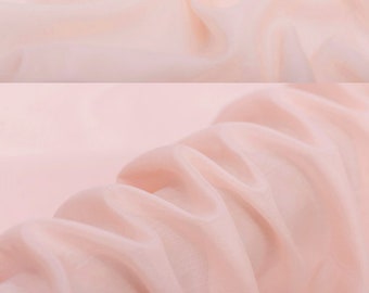 May include: A close-up of a pale pink silk fabric. The fabric is smooth and has a slight sheen. The fabric is draped over a surface and has a few folds. The text "silkfabricdesigns.etsy.com" is visible in the lower center of the image.