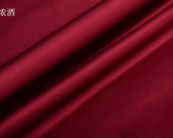 May include: A close-up of a deep burgundy fabric with a satin finish. The fabric is draped, creating soft folds and shadows. The number 15 and Chinese characters are in the upper left corner.
