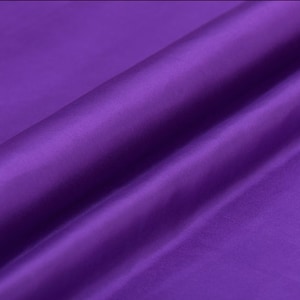 Może przedstawiać: Zbliżenie na gładką, fioletową tkaninę. Tkanina jest złożona w sposób, który pokazuje jej fakturę i połysk.
