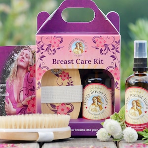 以下が含まれることがあります： 木製のブラシ、オイルボトル、小さなバームの入った瓶が見える透明な窓が付いた、紫とピンクの箱。箱には「Natural Breast Care Est. 2003」と「Breast Care Kit」と書かれている。ボトルと瓶にはどちらも「The Original Happy Breast Balm Natural Breast Care」と書かれている。