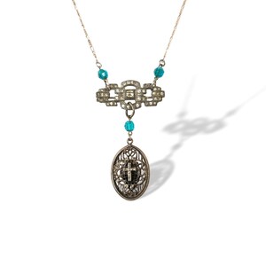 May include: Silver-toned necklace featuring a decorative rectangular centerpiece with clear rhinestones and turquoise beads. An oval pendant with a cross design hangs below. The necklace is on a white background.