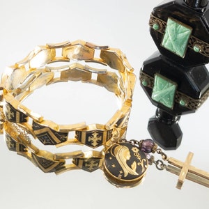 May include: A gold-tone bracelet with black enamel and a pendant featuring a depiction of the Virgin Mary. The pendant is attached to a chain with a small cross charm.