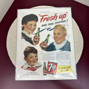 May include: A vintage 7 Up advertisement featuring three people holding bottles of the soda. The text reads "Fresh up and feel chipper!" and "Fresh up with Seven Up".