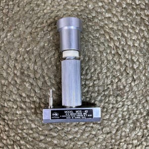 May include: A silver-colored metal O.K. Industries Model MOS-40 tool featuring a cylindrical handle with a textured grip, a white spacer, and a rectangular base plate with a small vertical pin and a black label with white printed text.