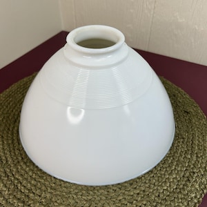 May include: A white glass lamp shade with a dome shape and a smooth, glossy finish. The upper section features a series of fine, horizontal concentric rings etched into the glass, leading up to a circular opening at the top for a light fixture.