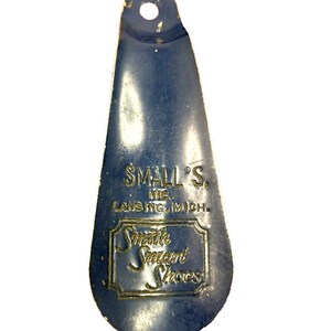 May include: A blue metal shoehorn with the text "Small's Inc. Lansing, Mich." and "Smith Smart Shoes" in gold lettering.