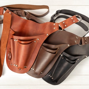 May include: Three leather tool belts in brown, dark brown, and black with multiple pockets and a belt loop.
