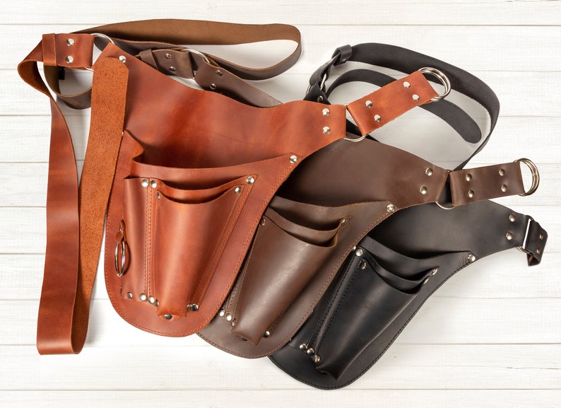 May include: Three leather tool belts in brown, dark brown, and black with multiple pockets and a belt loop.