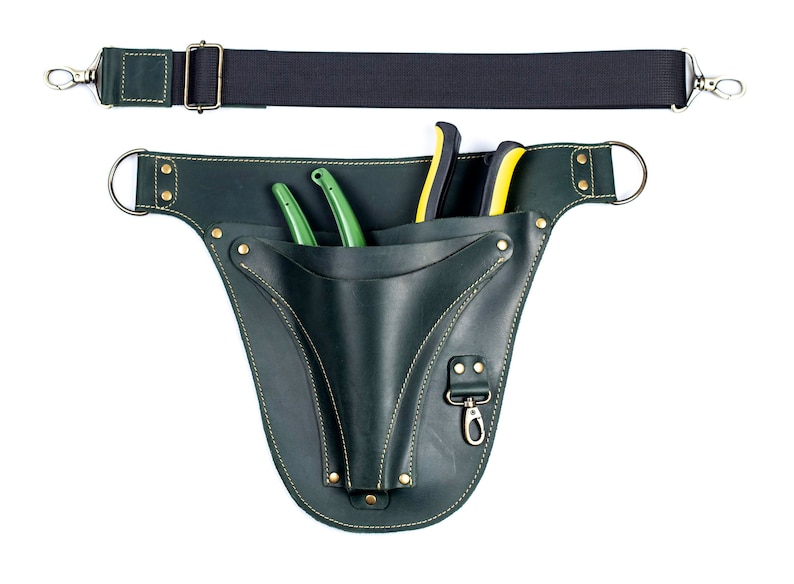 May include: A green leather tool belt with a black strap and two green pruning shears. The belt has a gold buckle and a small pocket with a metal hook.