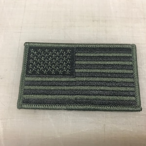 May include: A green embroidered American flag patch with black stitching.
