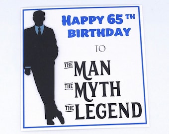 May include: A white card with a blue border and text that reads "Happy 65th Birthday To The Man The Myth The Legend." A black silhouette of a man in a suit is on the left side of the card.