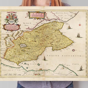 Op de afbeelding: Een vintage kaart van Fife, Schotland, met gedetailleerde geografische kenmerken en tekst. De kaart heeft een decoratieve cartouche en illustraties van schepen. De kaart is gedrukt op verouderd papier.