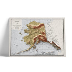 May include: A framed vintage map of Alaska, displaying the state's topography in shades of brown and gold. The map includes geographical details and text, set against a light background. The frame is a neutral colour.