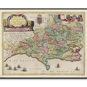 Op de afbeelding: Een ingelijste, antieke kaart van Dorset, Engeland, met gedetailleerde graafschapsindelingen in groen, roze en geel. De kaart bevat Latijnse tekst, illustraties van schepen en decoratieve cartouches.