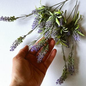Puede incluir: Un manojo de espigas de lavanda artificial con flores moradas y hojas verdes.