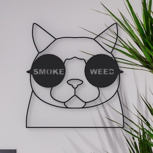 Pode incluir: Arte de parede de metal preto com um gato usando &oacute;culos de sol com as palavras "SMOKE" e "WEED" nas lentes.