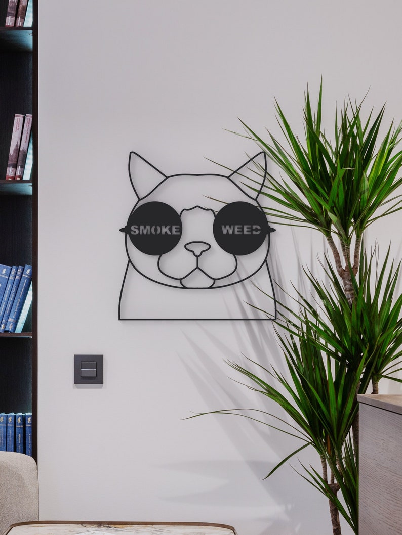 Pode incluir: Arte de parede de metal preto com um gato usando &oacute;culos de sol com as palavras "SMOKE" e "WEED" nas lentes.