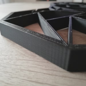 Pode incluir: Um design geom&eacute;trico hexagonal preto impresso em 3D. O design &eacute; feito de v&aacute;rios tri&acirc;ngulos e tem uma superf&iacute;cie texturizada.