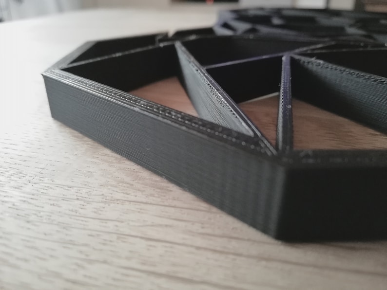Pode incluir: Um design geom&eacute;trico hexagonal preto impresso em 3D. O design &eacute; feito de v&aacute;rios tri&acirc;ngulos e tem uma superf&iacute;cie texturizada.