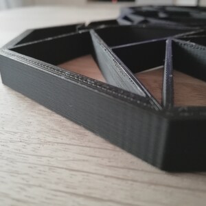 May include: A black 3D printed geometric design with a hexagonal shape. The design is made of multiple triangles and has a textured surface.