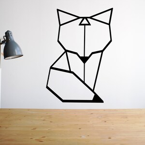 May include: Geometric black fox silhouette wall decal on a white wall. The decal is above a wooden table with a lamp on it.
