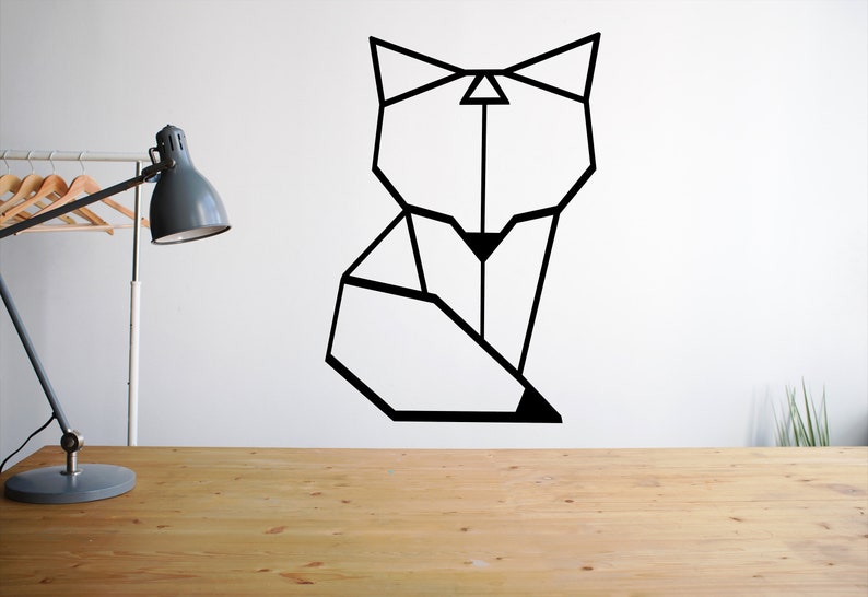 May include: Geometric black fox silhouette wall decal on a white wall. The decal is above a wooden table with a lamp on it.