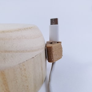 May include: A white USB cable with a brown wooden cable organizer. The cable is attached to a white USB-C connector.