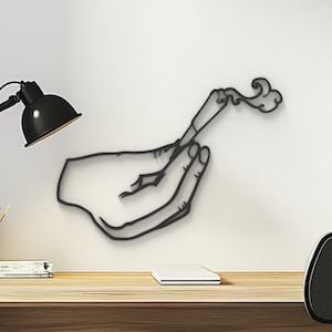 May include: Black metal wall art depicting a hand holding a lit joint with smoke rising from it.