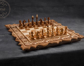 Puede incluir: Un juego de ajedrez de madera con detalles tallados intrincados en el tablero y las piezas. El tablero es un patrón de tablero de ajedrez tradicional con cuadrados claros y oscuros. Las piezas son de madera y tienen un acabado natural.