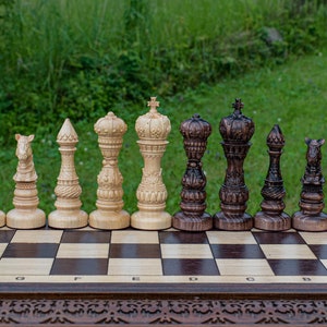 Könnte beinhalten: Ein Schachspiel aus Holz mit hell- und dunkelbraunen Figuren, die auf einem Schachbrett angeordnet sind. Die Figuren sind aufwendig geschnitzt und weisen verschiedene Designs auf.