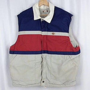 May include: A vintage, sleeveless vest in a color block design. The vest features a white collar, blue upper section, a red midsection, and a light gray lower section. It has a button closure and two pockets.