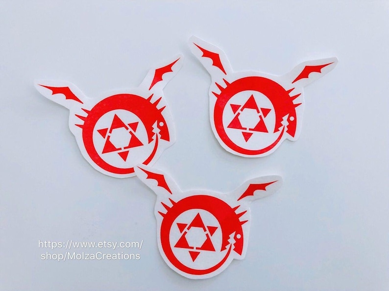 May include: Three red and white vinyl stickers featuring the alchemic symbol of the homunculus from the anime Fullmetal Alchemist. The symbol is a red circle with a white five-pointed star inside.