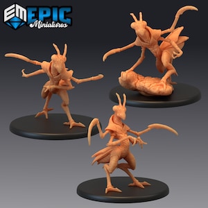 May include: Three miniature figures of humanoid mantis creatures with detailed sculpting and a beige colour. The figures are posed in dynamic stances with their limbs extended. The figures are standing on black circular bases.