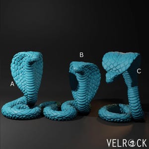 May include: Three turquoise cobra sculptures with detailed scale textures are displayed against a dark background. The cobra on the left is coiled, the middle one is upright, and the right one is in a striking pose. The sculptures are labeled A, B, and C.
