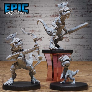 May include: Three gray miniature dragon figurines in armor, one with a sword, one with a bow and arrow, and one smaller figure. The figurines are on black bases, with the text "EPIC Miniatures" in the upper left corner.