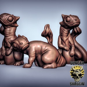 May include: Three brown ceramic figurines of stylised lizards with closed eyes. The lizards are in various poses, with one sitting upright, one lying down, and one standing on its hind legs.