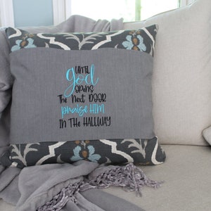 May include: A gray and blue throw pillow with the text "Until God opens the next door praise Him in the hallway".