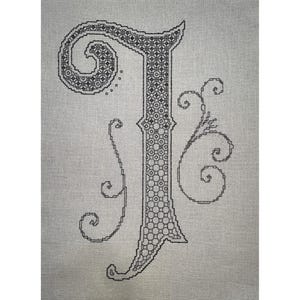 Könnte beinhalten: Schwarze und weiße Kreuzstich-Stickerei des Buchstabens "J" mit dekorativen Verzierungen.