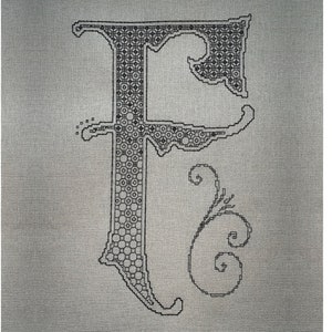 May include: A black cross-stitch embroidery of the letter F on a grey fabric background. The letter features an intricate geometric pattern of circles and lines within its structure, accompanied by a decorative swirling flourish to the right side.