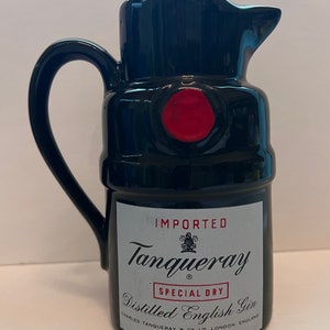 Op de afbeelding: Zwarte keramische kan in de vorm van een Tanqueray-ginfles. De fles heeft een rode zegel en de tekst "IMPORTED Tanqueray SPECIAL DRY Distilled English Gin CHARLES TANQUERAY & CO LTD LONDON, ENGLAND PRODUCE OF ENGLAND"