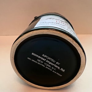 Op de afbeelding: Zwarte keramische fles met een wit etiket met de tekst "IMPORTED BY somerset importers, Itd. NEW YORK, N.Y. 100% GRAIN NEUTRAL SPIRITS. 94.6 PROOF"