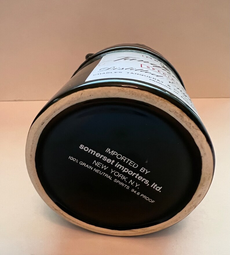 Op de afbeelding: Zwarte keramische fles met een wit etiket met de tekst "IMPORTED BY somerset importers, Itd. NEW YORK, N.Y. 100% GRAIN NEUTRAL SPIRITS. 94.6 PROOF"