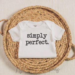 Puede incluir: Un body blanco para beb&eacute; con texto negro que dice "simply perfect."