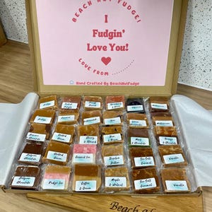 May include: A box of assorted fudge, with a pink lid saying "Beach Hut Fudge! I Fudgin' Love You!" and a heart. The box contains individually wrapped fudge squares in flavours such as Belgian Chocolate and Sea Salt Caramel.