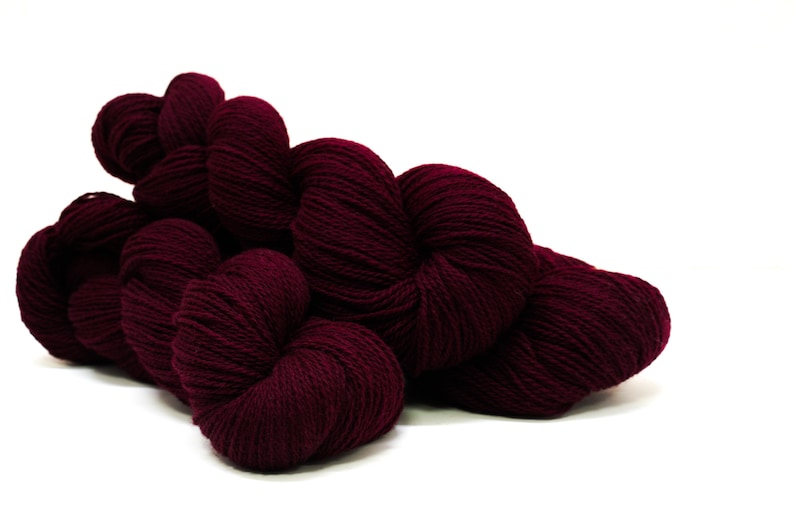 May include: A skein of deep burgundy yarn, wound into a ball shape.